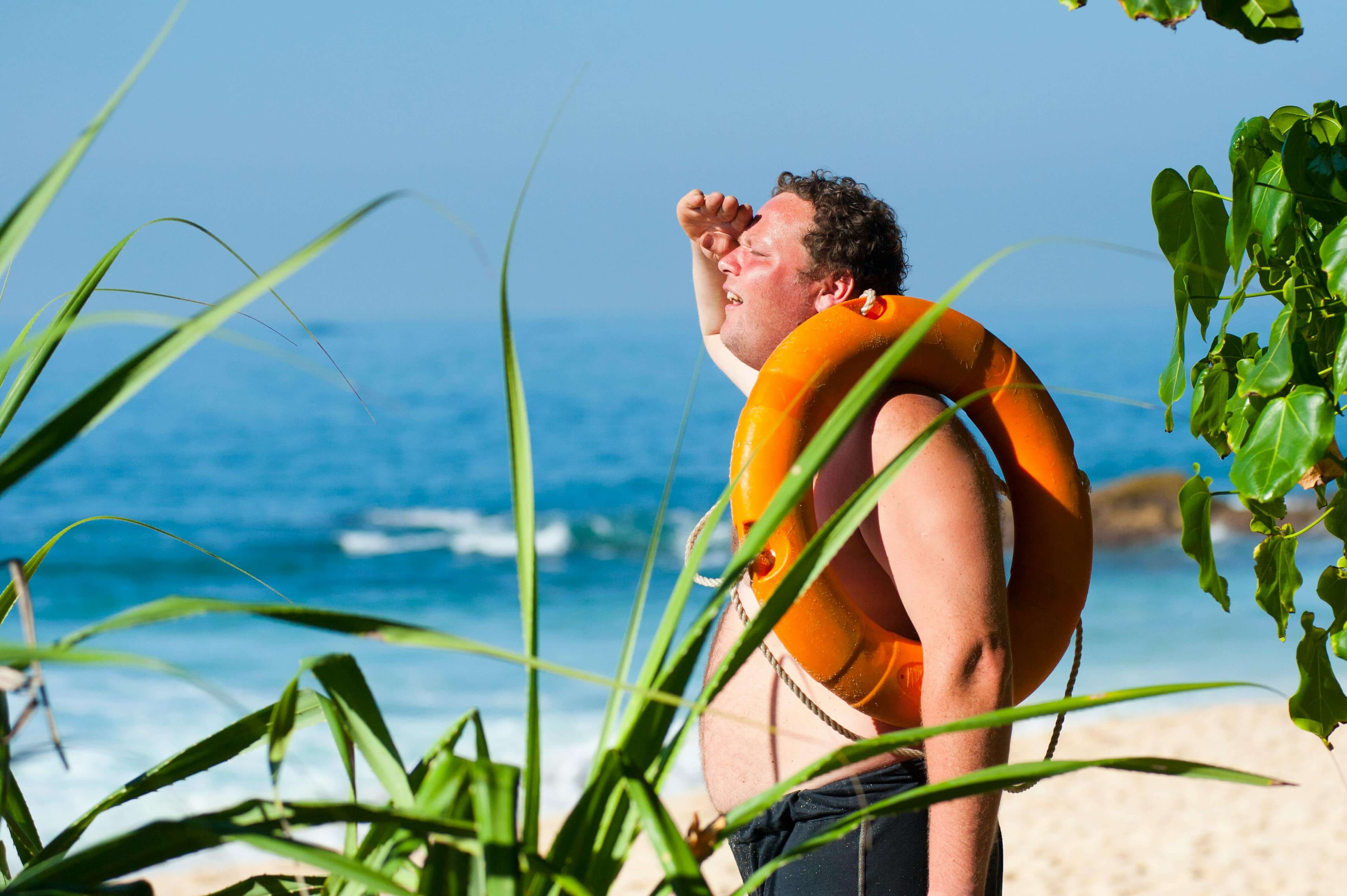 guy with floatation device looking out at ocean